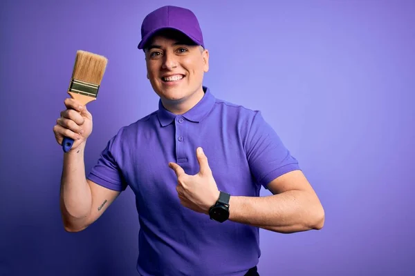 Jovem Pintor Decorador Moderno Homem Segurando Pincel Sobre Fundo Roxo — Fotografia de Stock