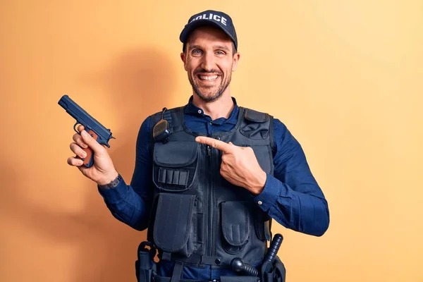 Üniformalı Yakışıklı Bir Polis Memuru Sarı Arka Planda Silah Tutan — Stok fotoğraf