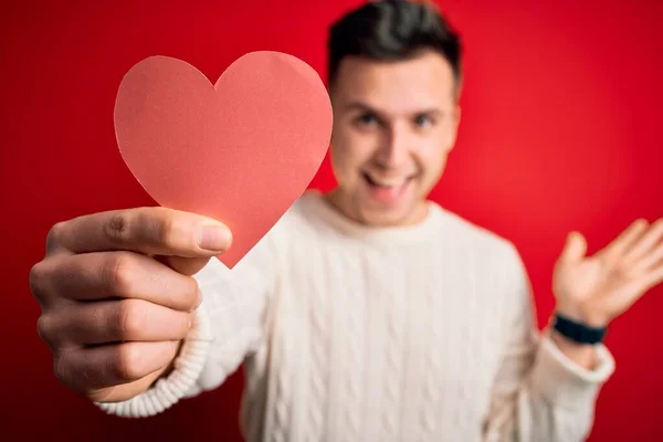 Young Handsome Caucasian Man Holding Paper Shape Heart Red Background — Stock Photo, Image