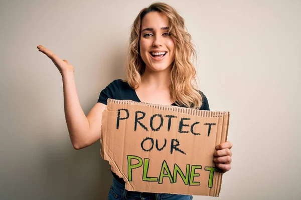 Young activist woman asking for environment holding banner with protect planet message very happy and excited, winner expression celebrating victory screaming with big smile and raised hands