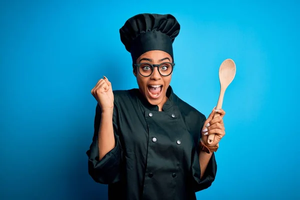 身穿炊具制服 头戴木勺工具的年轻非洲女厨师自豪地尖叫着 庆祝胜利和成功 激动地欢呼着 — 图库照片
