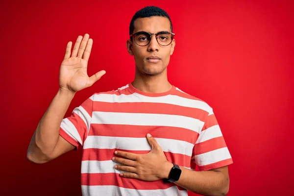 잘생긴 아프리카 미국인 남자가 줄무늬 티셔츠와 안경을 착용하고 손바닥을 서약을 — 스톡 사진