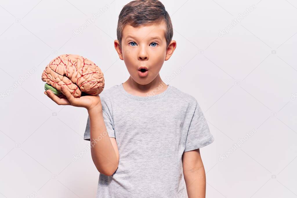 Cute blond kid holding brain scared and amazed with open mouth for surprise, disbelief face 