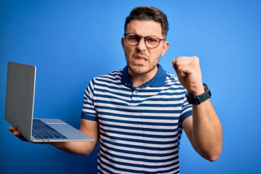 Mavi gözlü, gözlüklü genç bir iş adamı bilgisayarla çalışıyor. Sinirli ve sinirli bir şekilde bağırıyor, çıldırıyor ve el kaldırarak bağırıyor. Öfke kavramı.