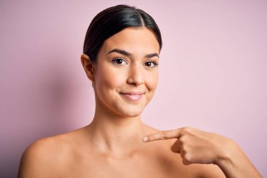 Soyutlanmış pembe arka planda duran genç ve güzel bir kız.