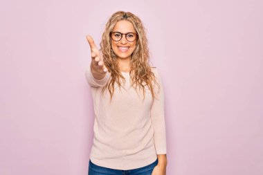 Genç, güzel, sarışın bir kadın pembe arka planda günlük süveter ve gözlük takıyor. Dostça bir selamlama ve hoş geldin hediyesi olarak gülümsüyor. Başarılı bir iş..