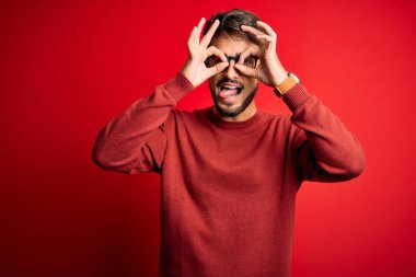 Sakallı, gözlüklü ve süveterli genç adam kırmızı arka planda dikiliyordu. Dürbün gibi hareket ediyordu. Dilini çıkarıyordu. Çılgın ifade.