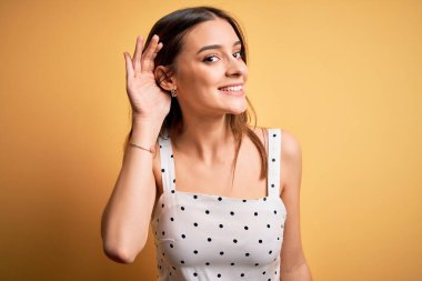 Sarı arka planda dikilen sıradan bir elbise giyen genç, güzel esmer kadın. Kulağından kulağa gülümseyen ve dedikodulara kulak misafiri olan. Sağırlık kavramı.