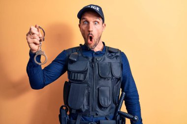 Üniforma giyen yakışıklı bir polis memuru ve sarı arka planda elleri kelepçeli bir kurşunla şaşırmış ve şaşırmış bir şekilde ağzı açık kalmış, güvenilmez bir yüz.