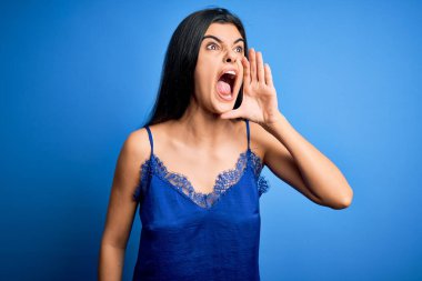 Zarif ve rahat mavi iç çamaşırı giyen genç, güzel esmer kadın bağırıyor ve ağızdan ağıza bağırıyor. İletişim konsepti.