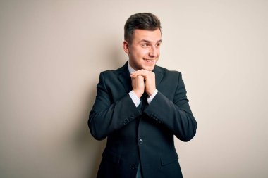 Zarif takım elbiseli ve kravatlı genç yakışıklı bir iş adamı izole arka planda gergin ve heyecanlı bir şekilde çene kenarına bakıyor.