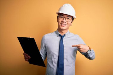 Güvenlik kaskı takan genç, yakışıklı Çinli mühendis elinde bir pano ve kendini gösteren sürpriz bir yüz var.