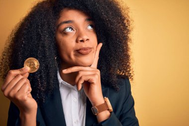Afro saçlı, Bitcoin 'i sarı arka planda tutan Afro-Amerikalı genç bir iş kadını.