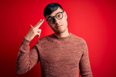 Kırmızı arka planda inek gözlüğü takan genç, yakışıklı İspanyol bir adam kendini vuruyor ve öldürüyor. Silah gibi el ve parmaklarını işaret ediyor. İntihar hareketi..