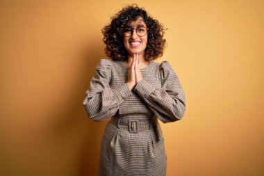 Güzel bir Arap iş kadını. Elbise ve gözlük takıyor. Sarı arka planda duruyor..