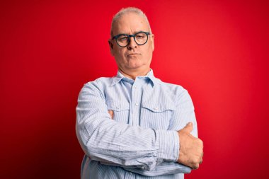 Orta yaşlı yakışıklı, beyaz bir adam kırmızı arka planda gözlük takıyor. Şüpheli ve gergin. Yüzünde çapraz kollu tasvip etmeyen bir ifade var. Negatif kişi.