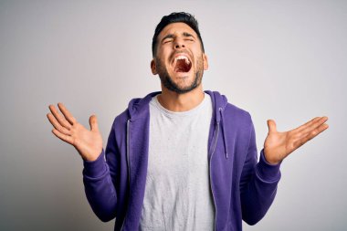 Mor eşofman üstü giyen genç yakışıklı adam, izole edilmiş beyaz arka planda ayakta duruyor ve kollarını kaldırıp heyecanla haykırarak başarının çılgınlığını kutluyor. Kazanan konsept