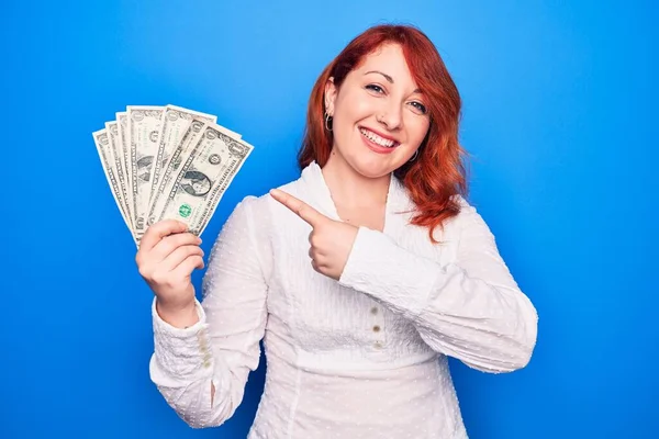Junge Schöne Rothaarige Frau Hält Ein Bündel Dollarnoten Über Blauem — Stockfoto