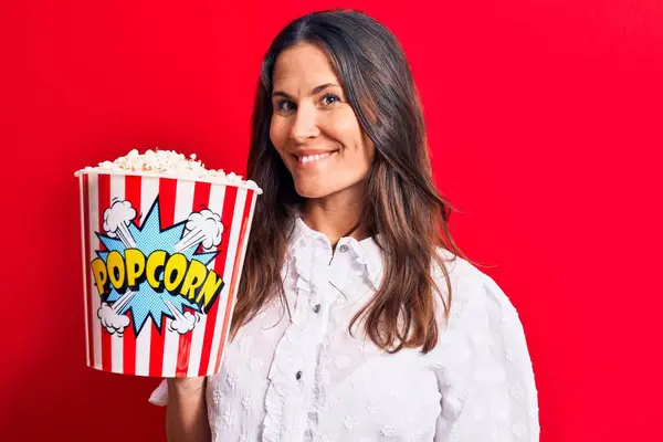 Young Beautiful Brunette Woman Eating Pack Popcorns Isolated Red Background — Stock Photo, Image