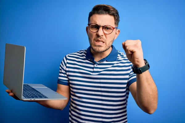Mavi gözlü, gözlüklü genç bir iş adamı bilgisayarla çalışıyor. Sinirli ve sinirli bir şekilde bağırıyor, çıldırıyor ve el kaldırarak bağırıyor. Öfke kavramı.