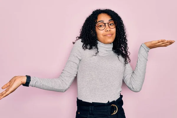 Młoda Afroamerykanka Swetrze Okularach Różowym Tle Nieświadoma Zdezorientowana Podniesionymi Rękami — Zdjęcie stockowe