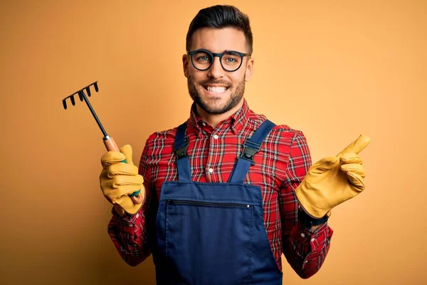 Junger Gärtner Arbeitsschürze Mit Handschuhen Und Werkzeug Über Gelbem Hintergrund — Stockfoto
