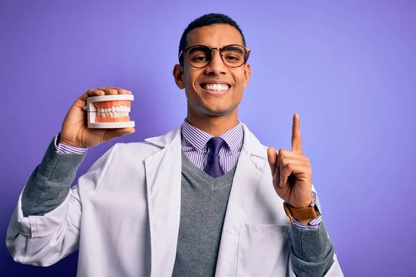 Young Handsome African American Dentist Man Holding Denture Teeth Purple — Stock Photo, Image