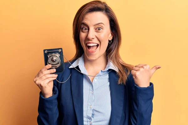 Young Beautiful Woman Holding Detective Badge Pointing Thumb Side Smiling — Stock Photo, Image