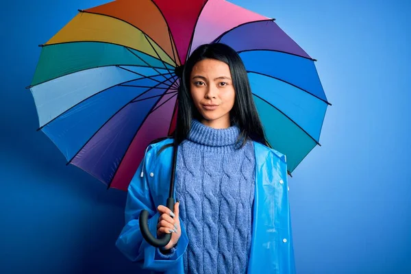 Jonge Chinese Vrouw Dragen Regenjas Houden Paraplu Geïsoleerde Blauwe Achtergrond — Stockfoto