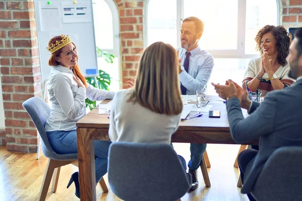 Group of business workers smiling happy and confident. Working together with smile on face applauding one of them wearing king crown at the office