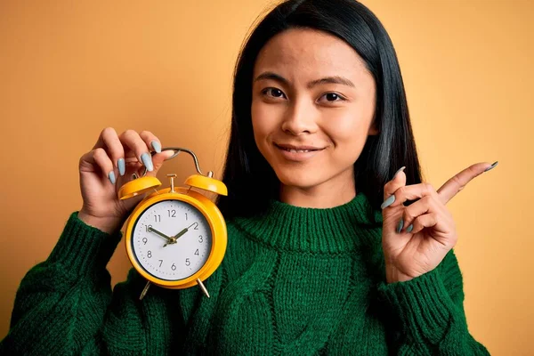 Junge Schöne Chinesin Hält Vintage Wecker Über Isolierten Gelben Hintergrund — Stockfoto