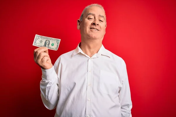 Człowiek Średnim Wieku Trzymający Banknot Dolarowy Nad Odizolowanym Czerwonym Tłem — Zdjęcie stockowe