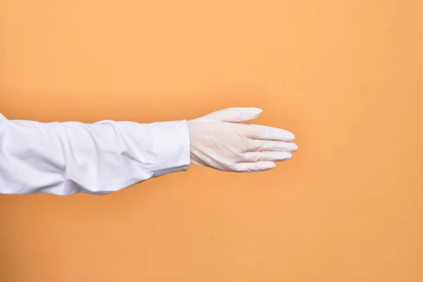 孤立した黄色の背景の上にハンドシェイクサインを行う医療外科手袋を身に着けている人の手 — ストック写真