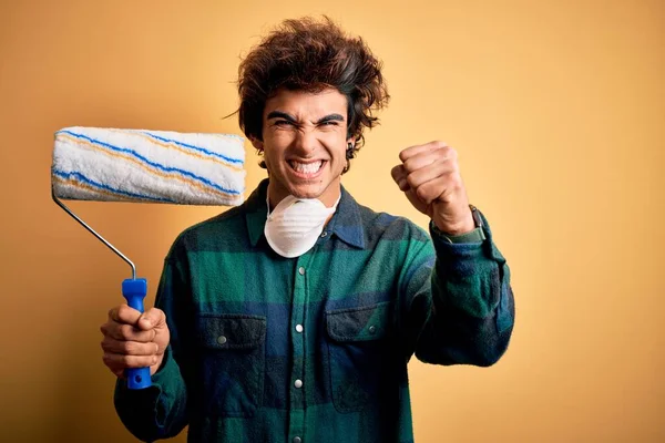 Jovem Pintor Bonito Homem Segurando Rolo Sobre Fundo Amarelo Isolado — Fotografia de Stock