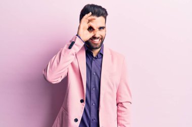 Sakallı, zarif ceketli, el hareketleriyle gülümseyen, mutlu yüzüyle parmaklarının arasından bakan yakışıklı genç bir adam.. 