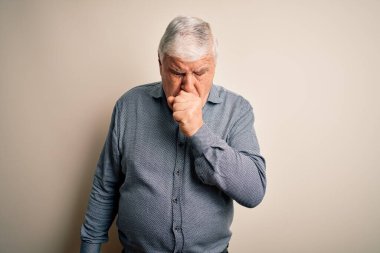 Üst düzey yakışıklı beyaz gömlekli adam izole edilmiş beyaz arka planda dikiliyor kendini iyi hissetmiyor ve soğuk algınlığı veya bronşitin belirtisi olarak öksürüyor. Sağlık hizmeti kavramı.