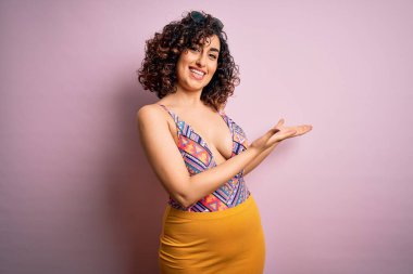 Genç, güzel bir Arap kadın tatilde. Pembe arka planda mayo ve güneş gözlüğü takıyor. Gülerek içeri girmeye davet ediyor.