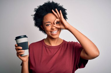 Kıvırcık saçlı, gülümseyen yüzüyle bir fincan kahve içen Afro-Amerikalı genç bir kadın.