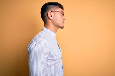 Sarı arka planda inek gözlüğü takan genç, yakışıklı İspanyol iş adamı. Yan tarafa bakıyor, rahat poz veriyor, kendine güvenen bir gülümsemesi var..