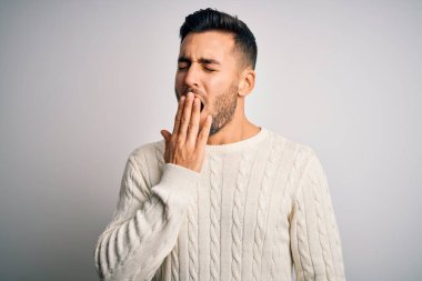 İzole edilmiş beyaz arka plan üzerinde duran sıradan süveter giyen genç yakışıklı adam ağzıyla esnemekten sıkılmış. Huzursuz ve uykulu..