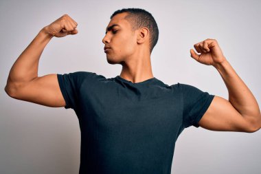 Beyaz arka planda duran ve gururla gülümseyen Afro-Amerikan tişörtü giyen genç ve yakışıklı bir adam. Fitness konsepti.