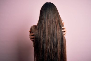Pembe arka planda şık süveter giyen güzel Asyalı bir kadın mutlu ve pozitif bir şekilde sarılıyor. Sevgi ve özgüven.