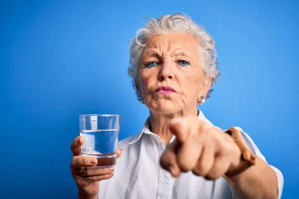 Starsza Piękna Kobieta Pije Szklankę Wody Stojącej Nad Odizolowanym Niebieskim — Zdjęcie stockowe