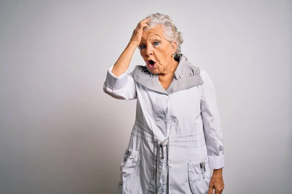 Senior beautiful grey-haired woman wearing casual jacket standing over white background surprised with hand on head for mistake, remember error. Forgot, bad memory concept.