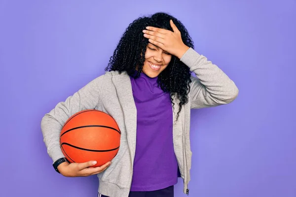 アフリカ系アメリカ人の女性は 紫色の背景に手で強調し 恥と驚きの顔 怒りと不満でショックを受けてバスケットボールボールを保持するスポーツをしている 恐怖と過ちへの動揺 — ストック写真