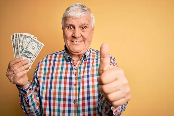 Starszy Przystojny Hoary Mężczyzna Trzyma Kilka Dolarów Banknotów Żółtym Tle — Zdjęcie stockowe