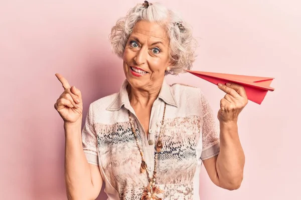 Ältere Grauhaarige Frau Hält Papierflugzeug Und Lächelt Glücklich Und Zeigt — Stockfoto