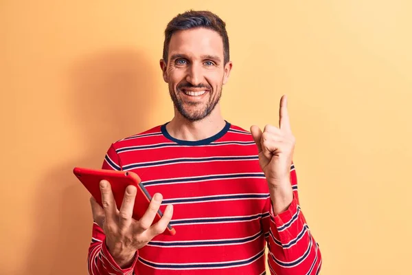 Joven Hombre Guapo Sosteniendo Touchpad Pie Sobre Fondo Amarillo Aislado —  Fotos de Stock