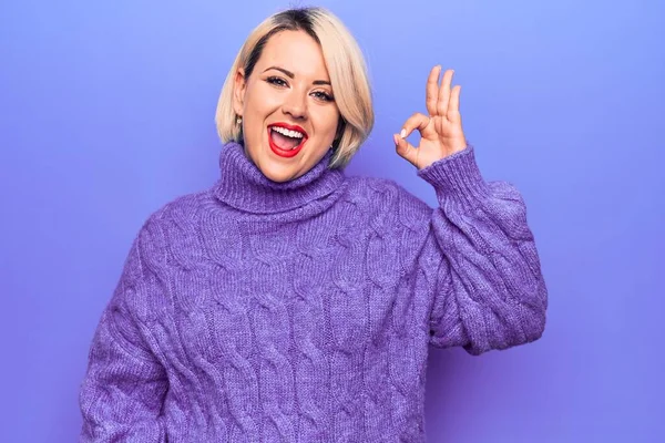 紫色の背景にカジュアルなタートルネックセーターを身に着けている美しいブロンドプラスサイズの女性は 手と指でOkサインを行い笑顔 成功した表現 — ストック写真