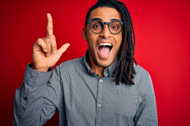 Rasta gömlekli ve gözlüklü Afro-Amerikan genç yakışıklı adam başarılı bir fikri işaret ediyor. Heyecanlı ve mutlu. Bir numara..